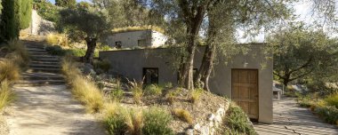 Teraslı arazide inşa edilmiş zeytin ağaçlarıyla çevrili modern bir ev. Ev ham betondan yapılmıştır. İçeride kimse yok.