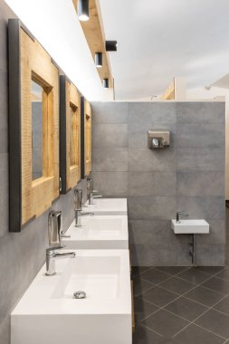 Üç lavabosu, aynası ve sabunu olan umumi tuvalet. Modern ve basit. Ön görünüm