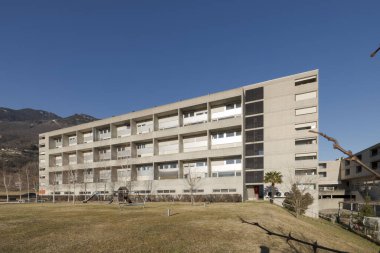 Önünde çocuklar ve diğer oyunlar için slaytları olan büyük bir bahçesi olan popüler bir apartman dairesi. Gökyüzü mavi ve içinde kimse yok..