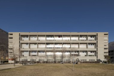 Önünde çocuklar ve diğer oyunlar için slaytları olan büyük bir bahçesi olan popüler bir apartman dairesi. Gökyüzü mavi ve içinde kimse yok..