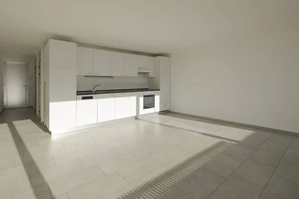 Renovated house interior with a white kitchen lit by the sun. White walls, no one inside