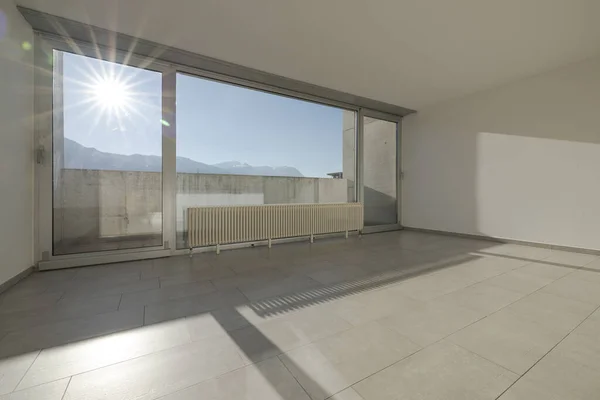 Large bright window with direct sun entering the room overlooking the Swiss mountains. Nobody inside