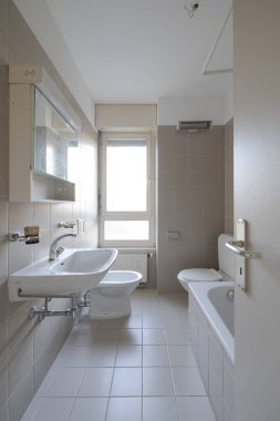 Parlak pencereli ve fayanslı eski bir banyo manzarası. Küvet de var. İçeride kimse yok.