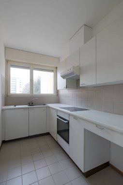 Fırını olan eski bir mutfak, indüksiyon ve lavabo. Parlak pencere. İçeride kimse yok.