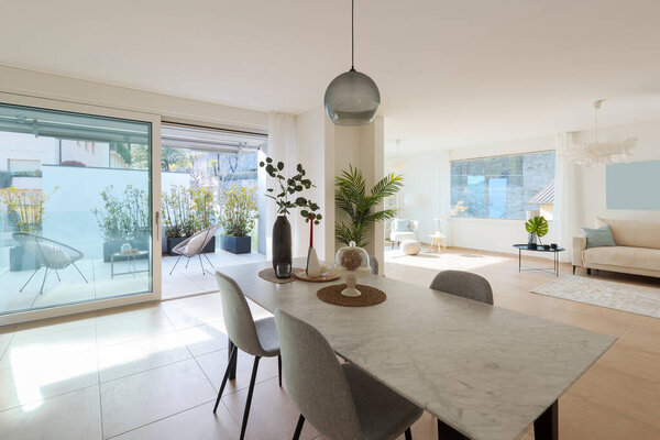 Interior of lounge and dining room. No one within that space. Modern flat, inside one sees a marble table and a sofa. Everything is tastefully furnished. Very Swiss style, cosy but cold everything perfect. 