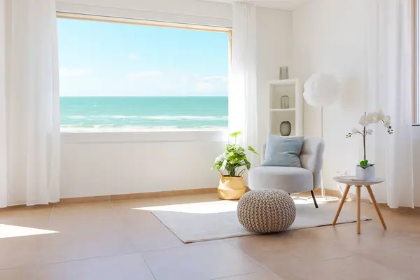 阳光明媚的日子里 有海景的公寓或客厅的细节 浪漫的空间 左边有大窗户 扶手椅和地毯 有一种和平与宁静的感觉 免版税图库图片