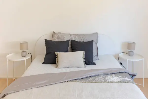 一张有很大枕头的双人床前的细节和毛毯移动 两边都有两个舒适的极简主义者 顶部都带着泡菜 干净而优雅 图库图片