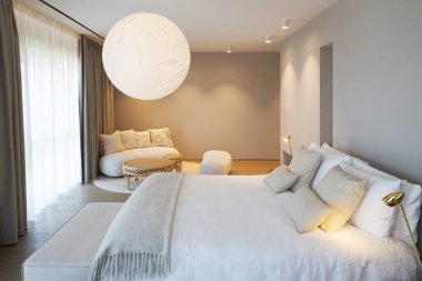 Rahat, modern, çift kişilik bir yatak odası. Odanın sonunda kanepesi ve koltuğu olan küçük bir salon.