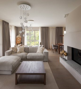 Hafif kanepesi, sehpası ve şöminesi olan minimalist oturma odası. Arkasında bahçeye bakan parlak bir pencere var. Doğal ışık, içeride kimse yok..