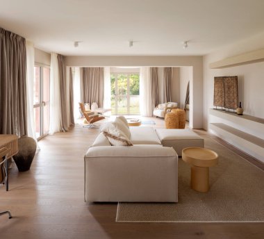 Odanın ortasında kanepesi olan çok amaçlı bir oda, yoga minderi, okuma koltuğu ve bahçeye bakan parlak bir pencere. İçeride kimse yok.