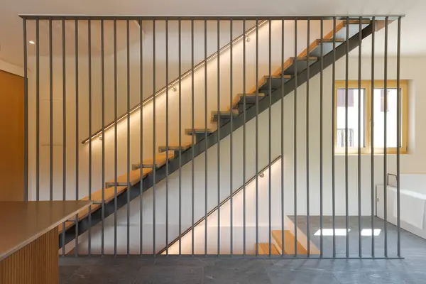 stock image Modern wooden staircase with metal support, handrail with led light underneath. Front view, no one inside