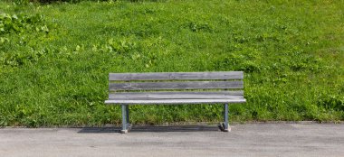 İsviçre dağ yolunun kenarındaki ahşap bankta. Kimse terlemiyor ama manzara romantik. Yeşil dağ çimlerinin etrafını ve arkasını görür.