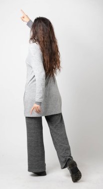 Arkadan uzun kahverengi saçlı, beyaz arka planda, sol üst köşesinde parmağı olan bir kadın. Stüdyo çekimi, izole edilmiş sahne