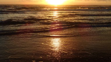 Yumuşak sahil dalgaları üzerinde gün doğumu yansıması