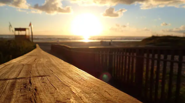 Ön planda ahşap korkuluklar, arka planda gün batımı, bulanık