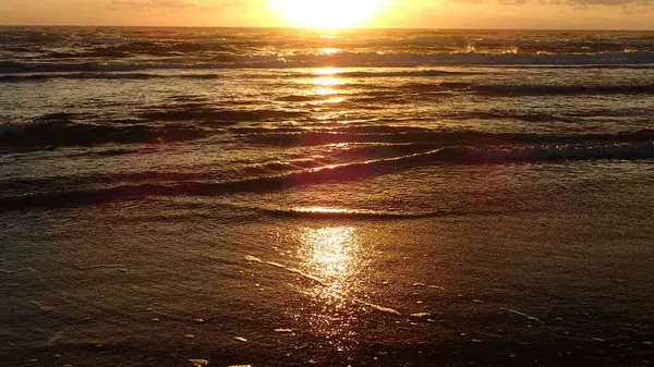 Yumuşak sahil dalgaları üzerinde gün doğumu yansıması