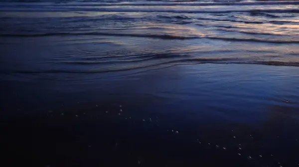 Kumsal dalgaları, karanlık ve biraz gün ışığı.