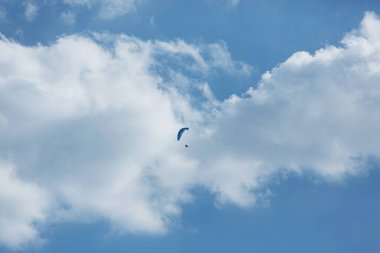 Mavi Paraglider güneşli bir günde bulutlarla gökyüzüne uçuyor..