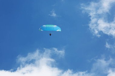 Mavi Paraglider güneşli bir günde bulutlarla gökyüzüne uçuyor..