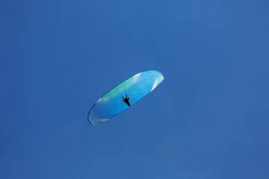 Mavi Paraglider güneşli bir günde bulutlarla gökyüzüne uçuyor..