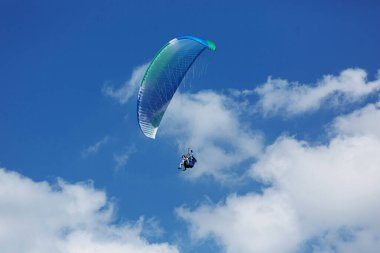 Mavi Paraglider güneşli bir günde bulutlarla gökyüzüne uçuyor..