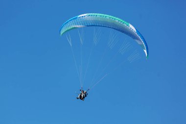 Mavi Paraglider güneşli bir günde bulutlarla gökyüzüne uçuyor..