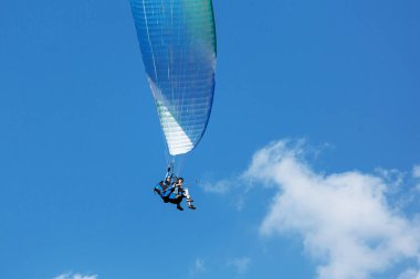 Mavi Paraglider güneşli bir günde bulutlarla gökyüzüne uçuyor..