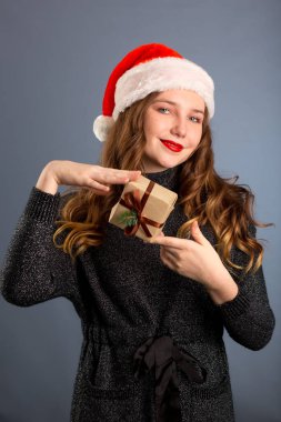 Beyaz bir kadın gri arka planda bir hediye tutuyor. izole..