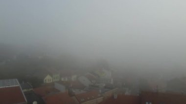 İnsansız hava aracı gün doğumunda sisli binalarla şehir manzarasına doğru uçuyor. Zemun, Belgrad. 4K.