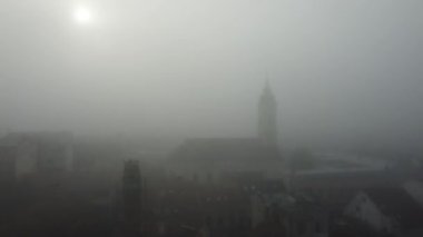 İnsansız hava aracı gün doğumunda sisli binalarla şehir manzarasına doğru uçuyor. Zemun, Belgrad. 4K.