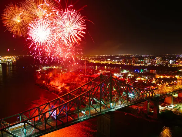 stock image Holiday fireworks above water with reflection near to Jacques Cartier Bridge, Jean-Drapeau park. Montreal, Quebec, Canada