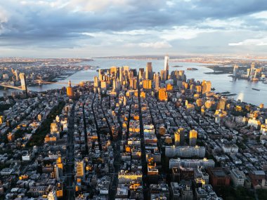 Manhattan 'ın şehir merkezindeki Hudson Nehri, Brooklyn ve New Jersey' nin güneş doğarken çekilmiş fotoğrafı. Arka planda bulutlar var. New York, ABD.