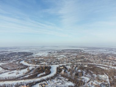 Kış boyunca Kazakistan 'ın Uralsk kentindeki donmuş nehrin yakınındaki karla kaplı evlerin hava manzarası. c.