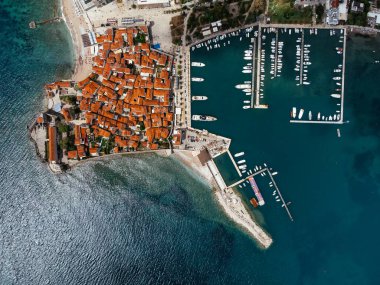 Karadağ 'ın Adriyatik kıyısındaki Budva kentinin marina ve kırmızı kiremitli çatılarıyla hava manzarası. g.