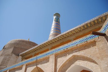 Kubbeli ve sivri kemerli, zengin boyanmış kiremitler, toprak tuğlalar ve ahşap panjurlar ve Özbekistan 'ın başkenti Khiva' da mavi bir gökyüzü ile donatılmış gözetleme kulesi ve dolgun duvarlar.