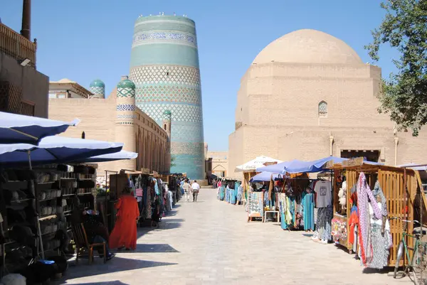 Kalta Minaresi zengin boyanmış kiremitler ve kubbeli kuleler ve tuğla ve toprak duvarlı binalar ve Özbekistan 'ın başkenti Khiva' da pazarı olan mavi bir gökyüzü ile süslenmiş.