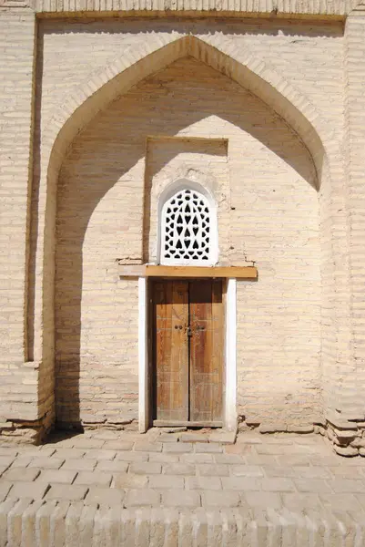 Güneş gören ahşap kapı ve pencere, Özbekistan 'ın başkenti Khiva' daki bir medresede tuğla uçlu bir kemer girişi.