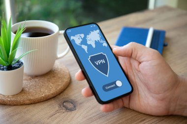 Kafe 'de, ekranda VPN uygulamalı erkek el telefonu.