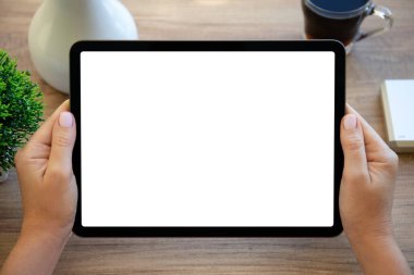 Kadın elleri, evdeki masanın izole ekran arka planına sahip bilgisayar tabletini tutuyor