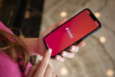 Alanya, Turkey - May 9, 2023: Woman hands holding Apple iPhone 14 with online Internet network service Tinder on the screen. clipart