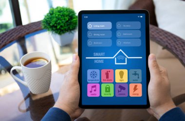 Man eller bilgisayar tabletini akıllı ev uygulaması ile birlikte apartmandaki masanın ekran arka planında tutar