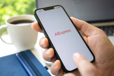 Alanya, Türkiye - 25 Mayıs 2023: İnternet alışveriş servisi Aliexpress ile iPhone 14 'ü tutan adam ekranda.