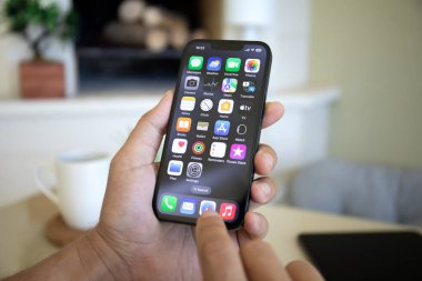 Alanya, Türkiye - 19 Eylül 2023: Ekranda IOS 17 ekranlı iPhone 14 ile el ele tutuşan adam.