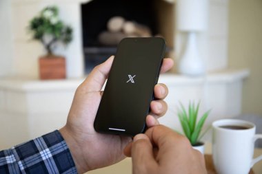 Alanya, Türkiye - 19 Eylül 2023: İnsan eli iPhone 14 ile sosyal ağ habercisi X Twitter ekranda.