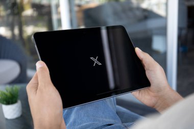 Alanya, Türkiye - 20 Eylül 2023: iPad Air Space Gray ile el ele tutuşan adam masadaki sosyal ağ servisi Twitter X ekranda