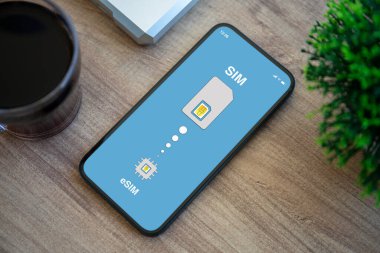 eSim 'de Sim kart değişimli telefon. Ofisteki ekran arkaplan masasında.