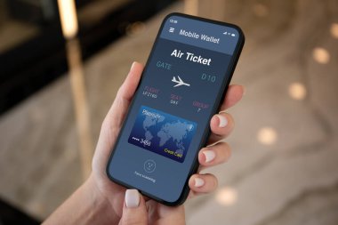 Havaalanında uçak bileti başvurusu yapan kadın el telefonu ekranda.