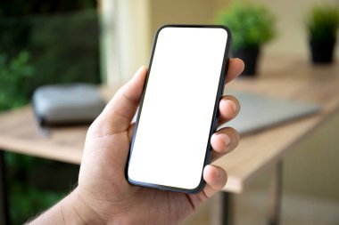 Adam el ele tutuşup ofisin arka planına bakıyor.