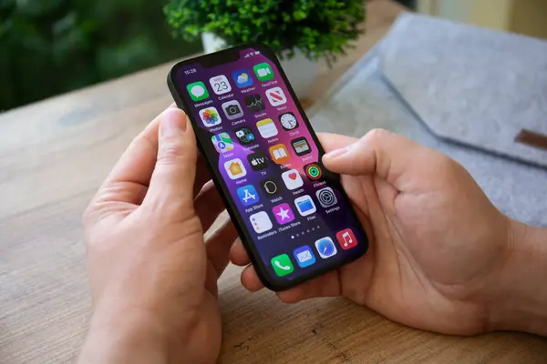 stock image Alanya, Turkey - February 23, 2022: Man hand holding iPhone 13 with home screen IOS 15 on the screen.