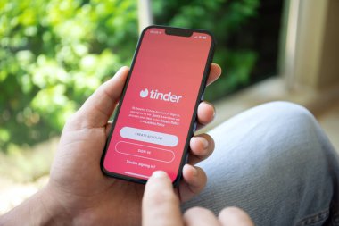 Alanya, Türkiye - 9 Haziran 2022: Çevrimiçi İnternet ağı Tinder ile iPhone 13 'ü tutan adam ekranda.